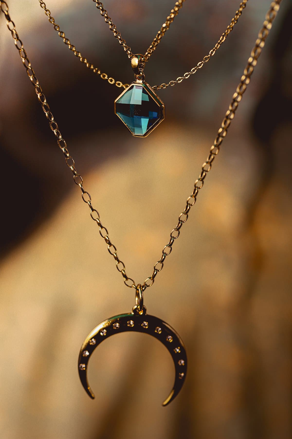 Layered golden necklaces in warm sunlight